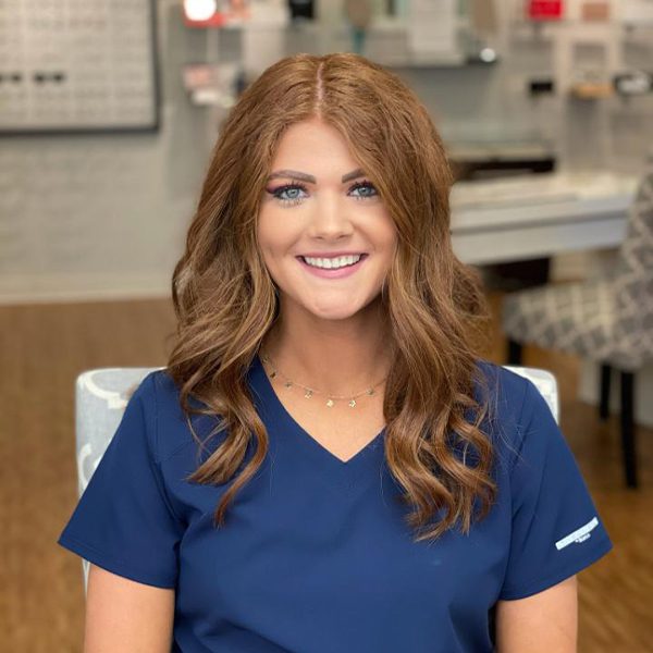 A woman in blue shirt sitting down smiling.